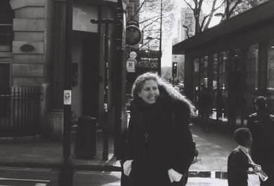 Smiling woman with daughter standing on footpath in city