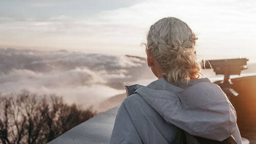 Rear view of woman looking at camera against sky