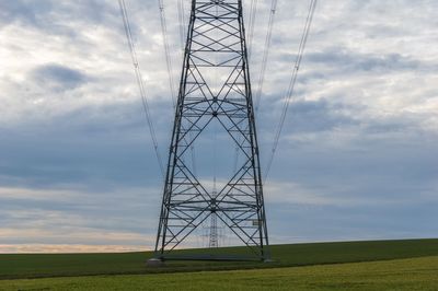 Low angle view of electricity pylon on field against sky