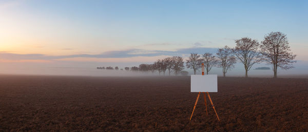 Blank art board and realistic wooden easel on the field. 