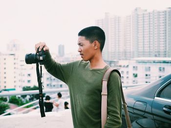 Full length of man photographing in city against sky