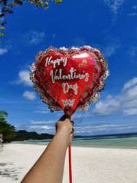 Close-up of hand holding heart shape against sky