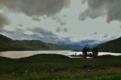 Scenic view of lake by field against sky