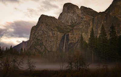 Scenic view of mountains and waterfall against sky