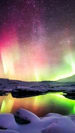 Scenic view of lake against aurora borealis in winter