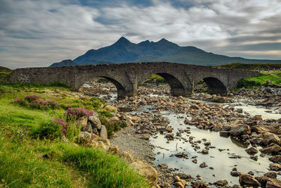 Arch bridge over mountains against sky