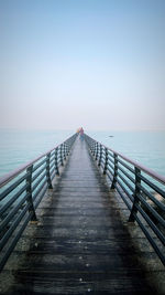 Empty pier over sea against clear sky