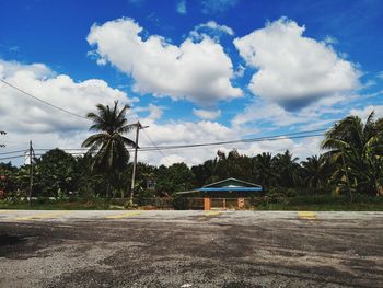 Road by trees and houses against sky