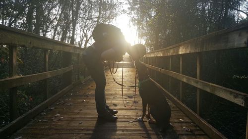 Side view of man kissing dog on footbridge