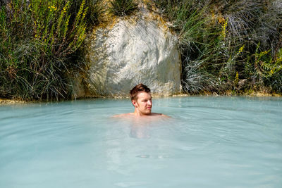 Portrait of shirtless man swimming in pool