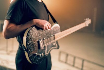 Midsection of man playing guitar on stage