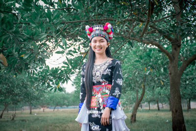 Portrait of a smiling young woman standing against trees