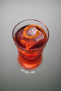 Negroni aperitif cocktail in polka dot glass with large ice and orange zest