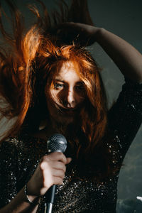 Portrait of redhead female singer woman in sparkly evening dress holding microphone. singer at