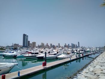 Boats moored at harbor against clear sky