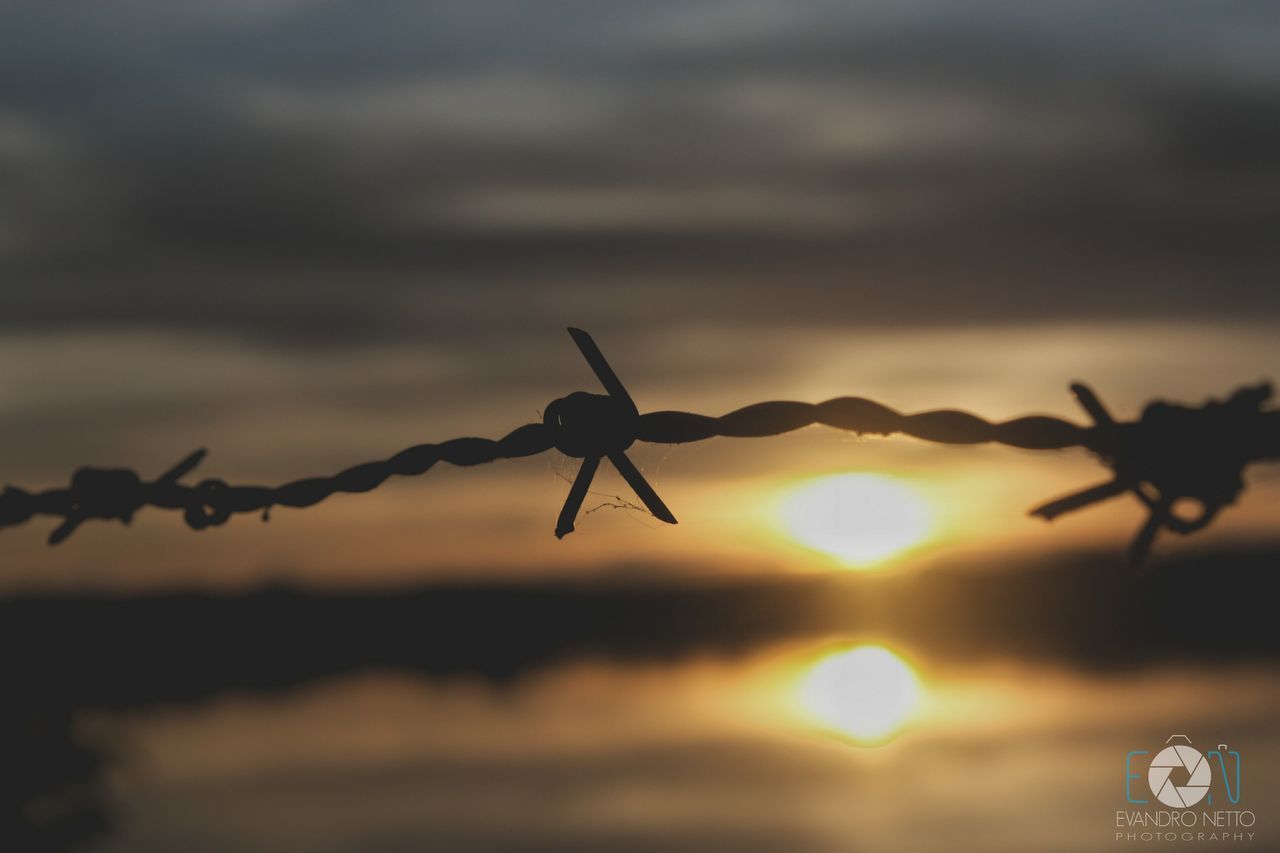 CLOSE-UP OF BARBED WIRE AGAINST SKY