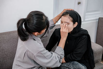 Side view of young woman sitting on sofa at home