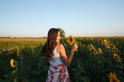 Midsection of woman standing in sunflower land