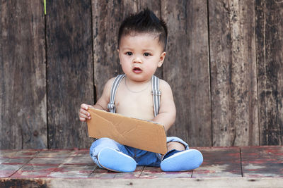 Portrait of cute boy sitting on wooden floor