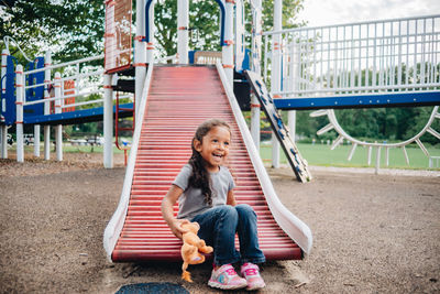 Full length of a smiling girl sitting on playground