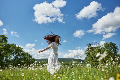 Rear view of woman standing on field against sky