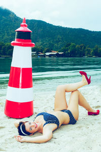 Portrait of mid adult woman in swimwear lying at lakeshore