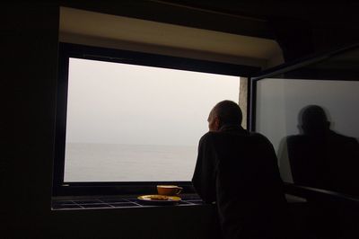 Rear view of men sitting on window