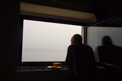 Rear view of man standing by window in boat