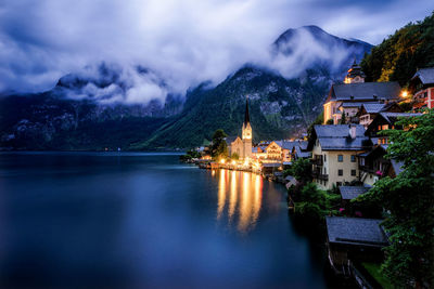 Lake by illuminated mountain against sky at dusk