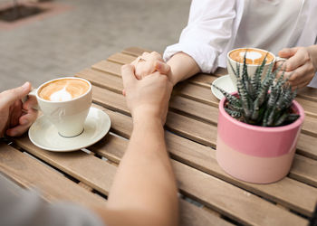 Couple holding hands and coffee outside closeup lateral top view.