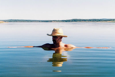 Full length of shirtless man in sea against sky