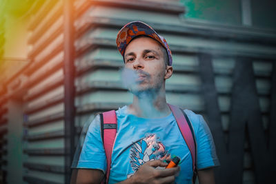 Portrait of young man standing against wall