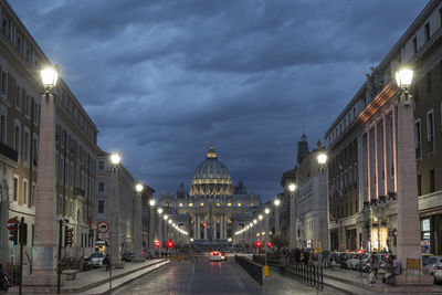 Road amidst buildings against sky at night