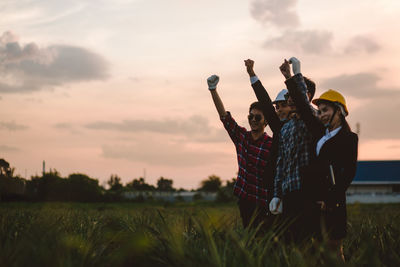 People standing on field against sky during sunset