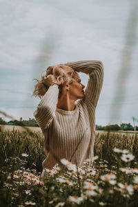 Woman with umbrella on field against sky