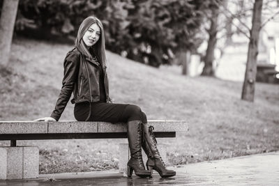 Portrait of young woman sitting on footpath in park