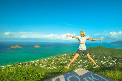 Rear view of woman jumping against sea