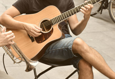 Midsection of man playing guitar in city