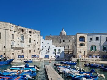 High angle view of seagulls on canal by buildings against blue sky