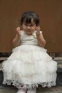 Portrait of cute girl standing against wall