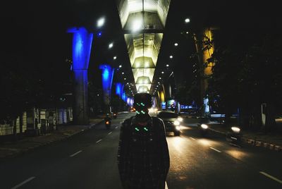 Man standing on illuminated road in city at night
