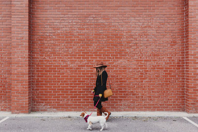 Full length of person on brick wall