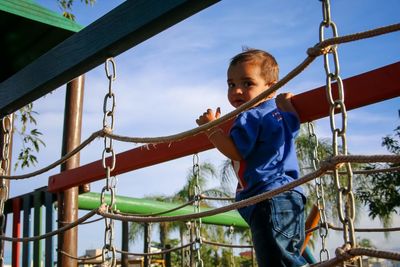 Boy playing on slide at playground against sky