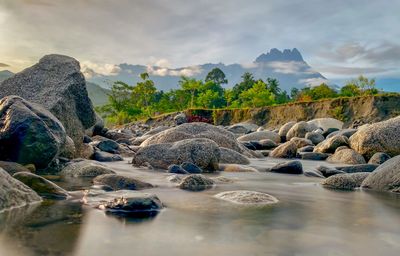 Rocks by lake against sky