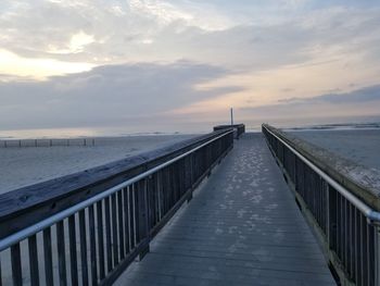 Pier over sea against sky during sunset