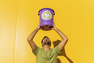 Full length of man standing against yellow wall