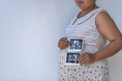 Close up of pregnant woman holding ultrasound scan on her tummy