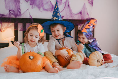 Three little kids in festive halloween costumes with pumpkins having fun. family spending time 