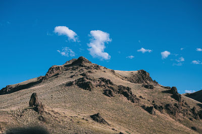 Low angle view of rocky mountain against blue sky