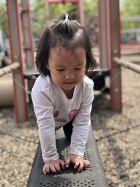 Cute girl crawling on equipment in playground